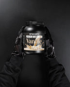 Vanilla whey protein powder container held by gloved hands on black background